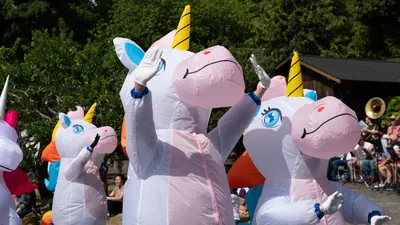 Parade participants in inflatable unicorn costumes wave to the crowd during the Fourth of July parade in Home, Washington.